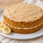 Two thin pumpkin-colored cake layers with pale tan filling and topping, beside banana slices.